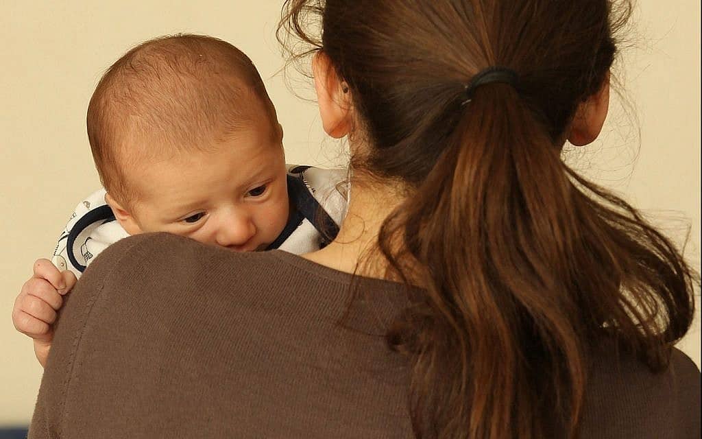 אישה מחזיקה בידיה תינוק (צילום: Nati Shohat/Flash90)
