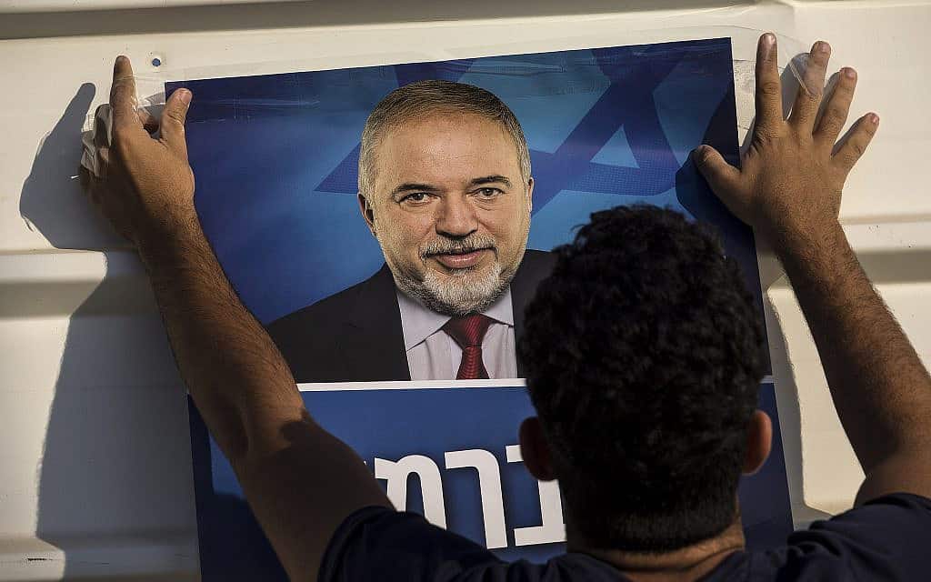 פעיל ישראל ביתנו תולה שלט עם תמונת אביגדור ליברמן לפני הבחירות בספטמבר, 2019 (צילום: AP Photo/Tsafrir Abayov)