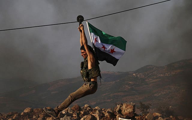 לוחם בצבא סוריה החופשית, אשר בתמיכת טורקיה, נושא את דגל הארגון במהלך אימונים בצפון סוריה לקראת הפלישה הטורקית, ב-7 באוקטובר 2019 (צילום: AP Photo)