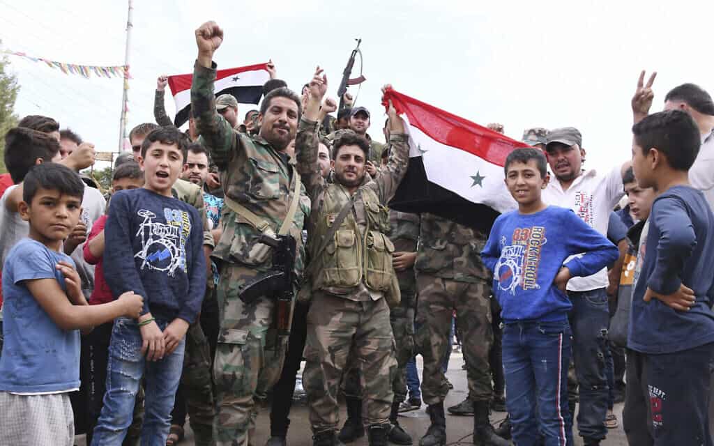 חיילים מניפים דגל סורי בכובאני, אוקטובר 2019 (צילום: SANA via AP)