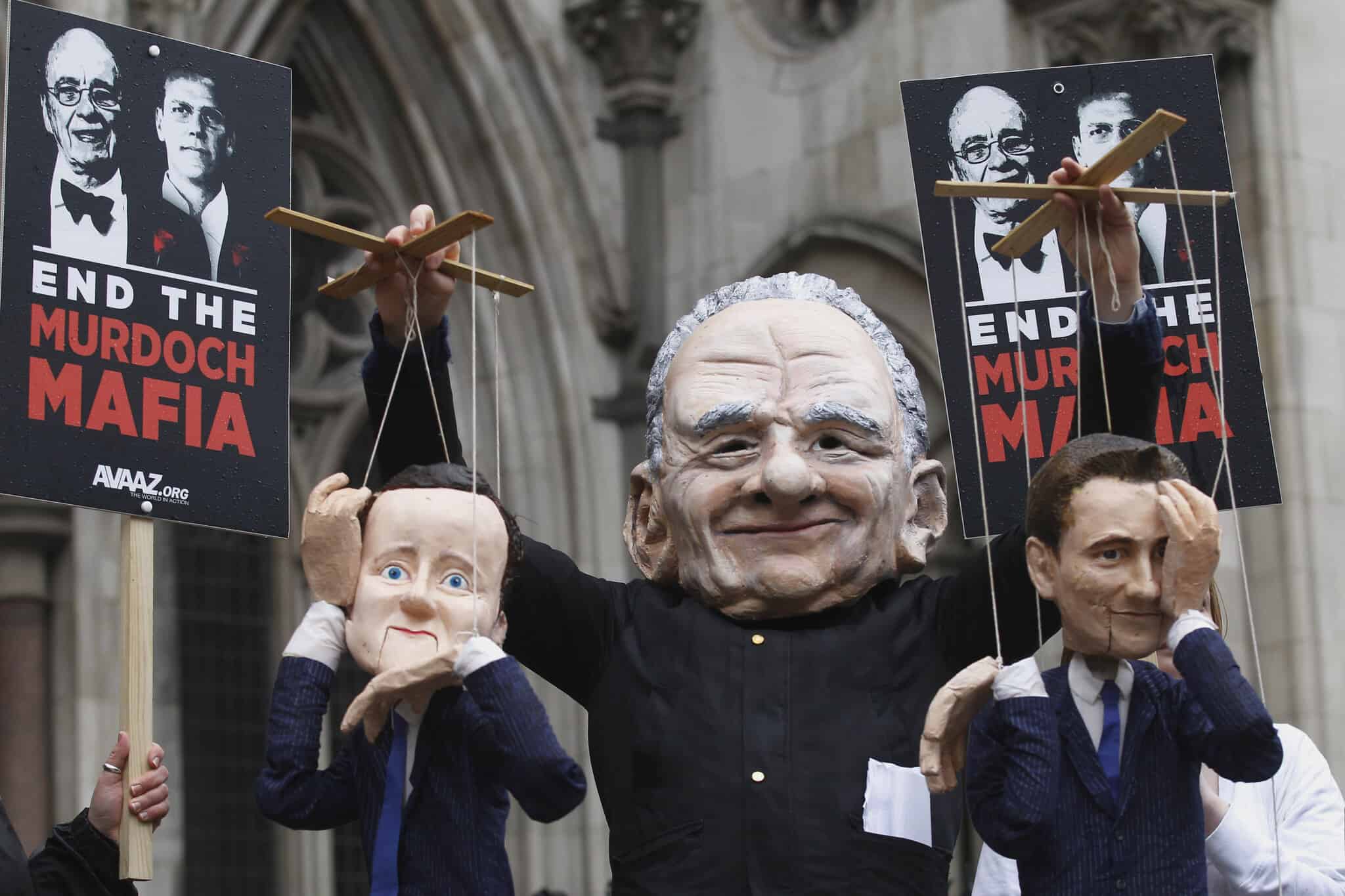 מחאה מחוץ לבית המשפט העליון בלונדון, במהלך חקירת לוויסון: מיצג של מרדוק מושך בחוטים של ראש הממשלה דיוויד קמרון ושר התרבות ג'יימס האנט. 25 באפריל 2012 (צילום: AP Photo/Sang Tan)