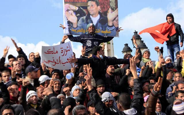 מפגינים בתוניסיה נושאים שלט ובו תמונה של מוחמד בו עזיזי, שהצית את עצמו (צילום: AP Photo/Salah Habibi)