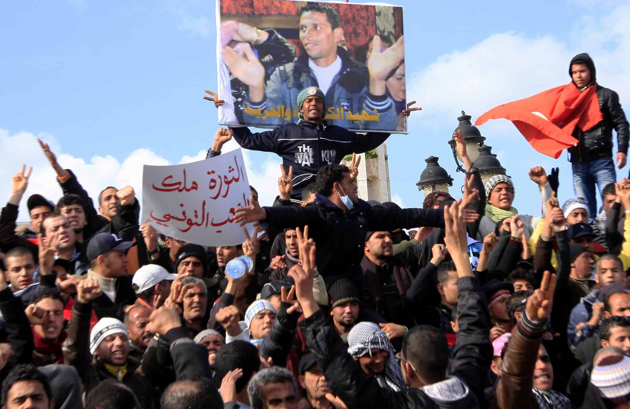 מפגינים בתוניסיה נושאים שלט ובו תמונה של מוחמד בועזיזי, שהצית את עצמו (צילום: AP Photo/Salah Habibi)