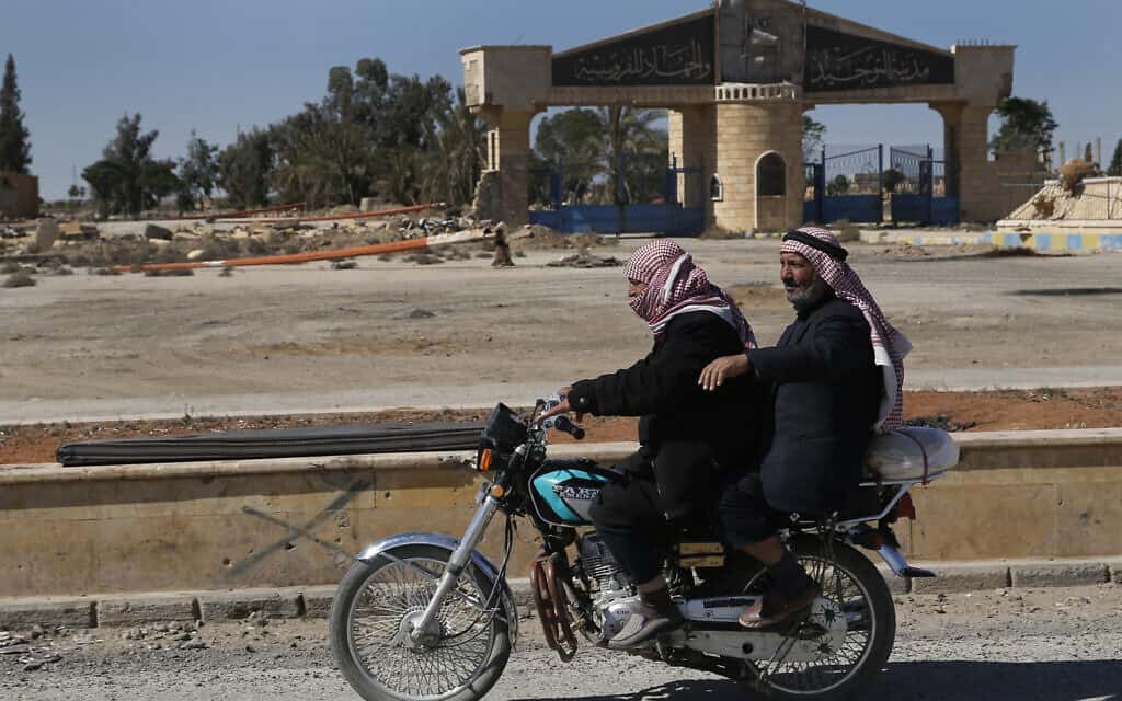 גברים סוריים חולפים ליד בית ספר מוסלמי שנהרס במלחמת האזרחים, 2018 (צילום: AP Photo/Hussein Malla))
