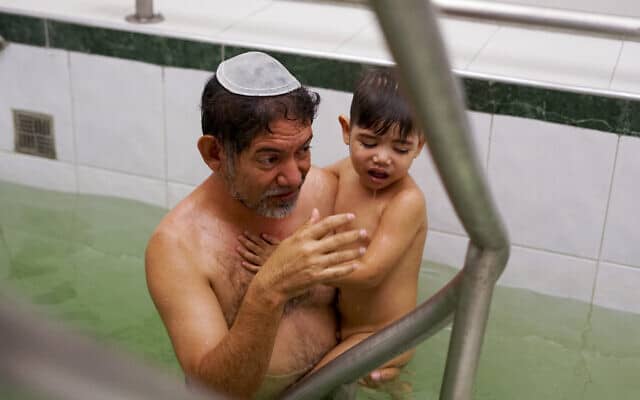 גבר מוונצואלה טובל עם בנו במקווה, במסגרת ניסיון מתוקשר להתקבל לחיק היהדות ולעלות לישראל, ארכיון, 2017 (צילום: AP Photo/Christine Armario)