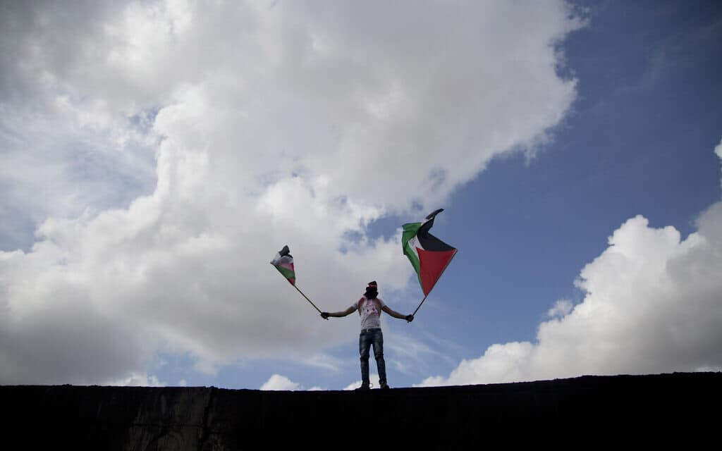 מפגין פלסטיני מטפס על החומה ליד אבו דיס, ארכיון, 2015 (צילום: AP Photo/Majdi Mohammed)
