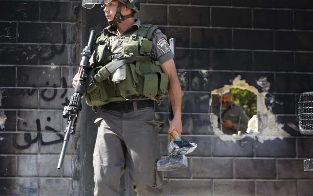 לוחם ישראלי שומר על חור בחומה המקיפה את אבו דיס, שיצרו אקטיביסטים פלסטיניים, ארכיון, 2013 (צילום: AP Photo/Majdi Mohammed)