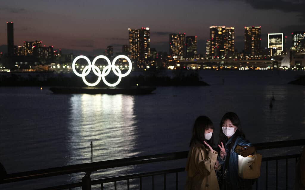 נשים מצטלמות על רקע הטבעות האולימפיות בטוקיו. מרץ 2020 (צילום: AP Photo/Jae C. Hong)