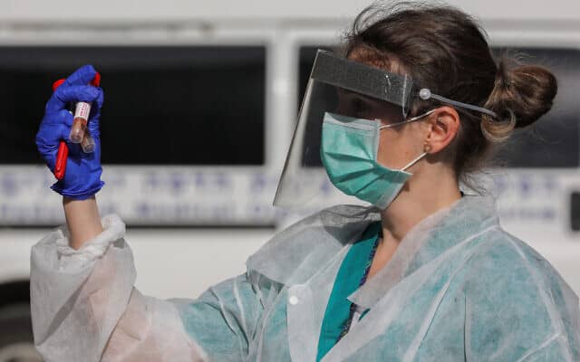 עובדת בצוות הרפואי בבית חולים הדסה עין כרם עם דגימת בדיקה לאבחון וירוס הקורונה. 26 במרץ 2020 (צילום: Olivier Fitoussi/Flash90)