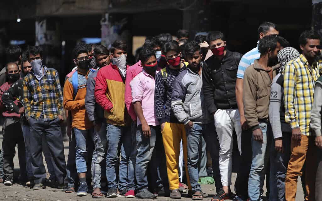 עובדים הודים שנתקעו הרחק מביתם עומדים בתור וממתינים לחלוקת אוכל, ב-22 במרץ 2020 (צילום: AP Photo/Channi Anand)