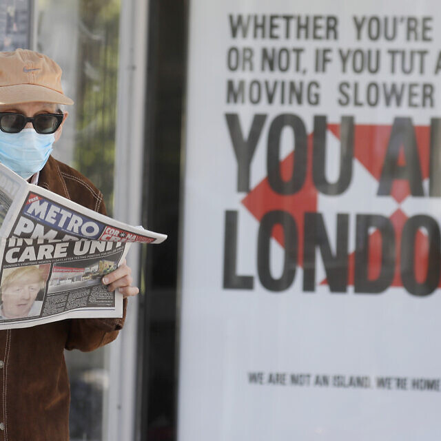 אדם בלונדון קורא עיתון שעל השער שלו הכותרת: ראש הממשלה בטיפול נמרץ. 7 באפריל 2020 (צילום: AP Photo/Kirsty Wigglesworth)