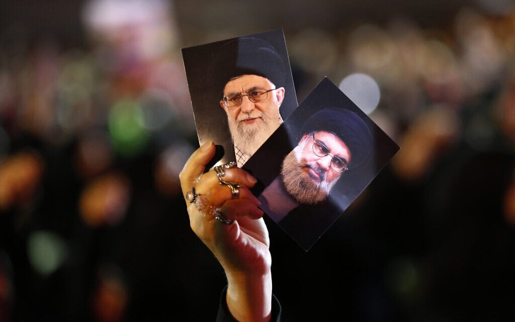 תומך חזבאללה מחזיק תמונות של מנהיג חזבאללה שיח' חסן נצראללה ושל המנהיג העליון של איראן אייטולה ח'מנאי (צילום: AP Photo/Hussein Malla)
