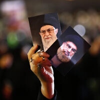 תומך חזבאללה מחזיק תמונות של מנהיג חזבאללה שיח' חסן נסראללה ושל המנהיג העליון של איראן אייטולה ח'מנאי (צילום: AP Photo/Hussein Malla)