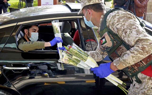 עידן הקורונה בירדן, חיילים מחלקים פרחים לתושבים שהיו נתונים בהסגר ממושך (צילום: Khalil Mazraawi/Pool via AP)