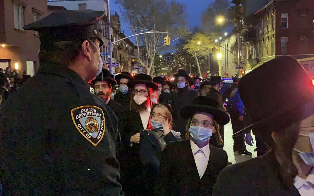 שוטר בעיר ניו יורק משגיח על מאות אבלים במסע הלוויה של הרב החסידי חיים מרץ, שנפטר לאחר שנדבק בנגיף הקורונה, בברוקלין, ניו יורק, 28 באפריל 2020 (צילום: פיטר גרבר באמצעות AP)