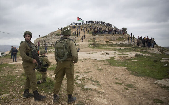 חיילים צופים במחאה פלסטינית נגד הסיפוח בגדה המערבית, מרץ 2020 (צילום: AP Photo/Majdi Mohammed, File)