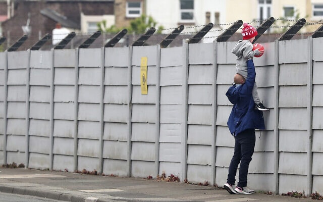 אבא מחזיק את ילדו כדי שיצפה באימון של ליברפול, ב-19 במאי 2020 (צילום: Peter Byrne/PA via AP)