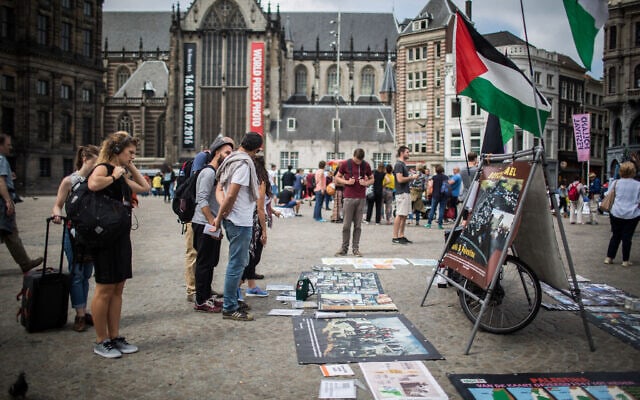 תיירים מסתכלים על דוכן BDS הכולל תמונות ודגלים פלסטינים, הקוראים לפלסטין החופשית. תצלום ארכיון מכיכר דאם במרכז אמטרדם (צילום: Hadas Parush/Flash90)