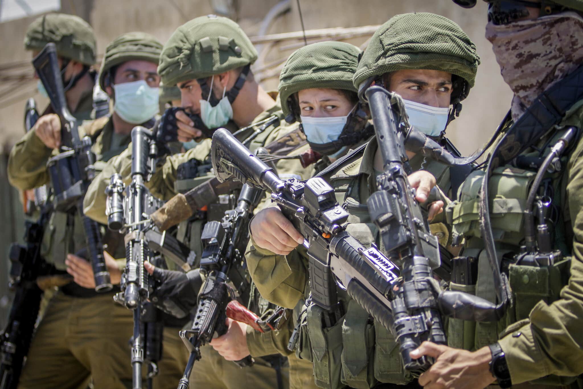 חיילים ישראלים מביטים במחאה פלסטינית נגד הסיפוח, יוני 2020 (צילום: Nasser Ishtayeh/Flash90)