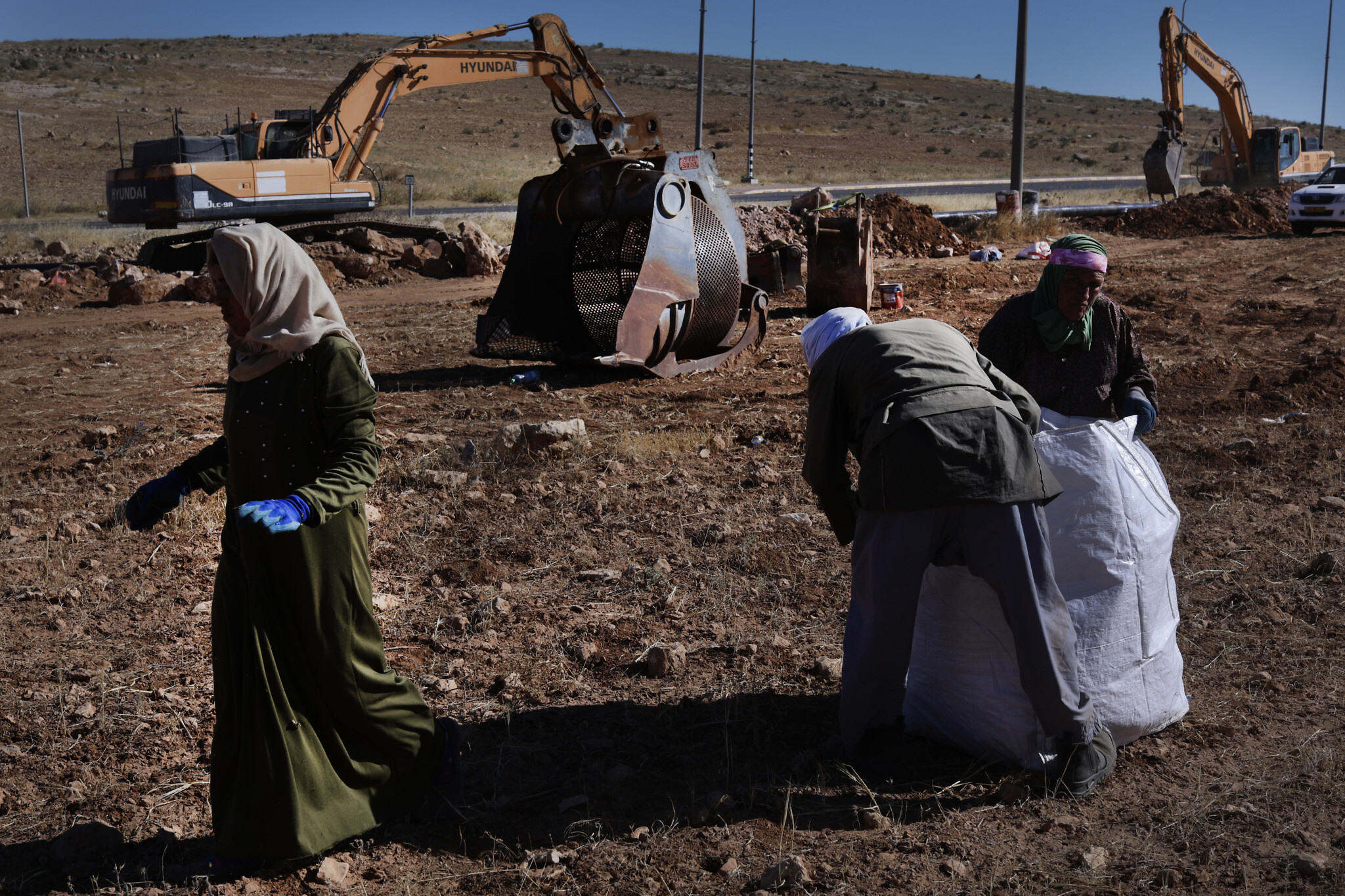 חאלד אבו-עבד וקרובת משפחה עובדים את האדמה ליד הכביש המוביל לסוסיא. מאחוריהם, הדחפורים של מקורות עובדים (צילום: אלדד רפאלי)