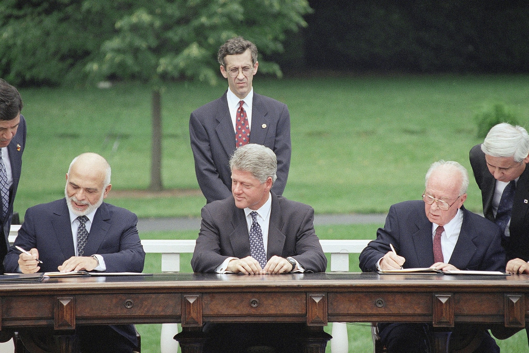 נשיא ארצות הברית ביל קלינטון מביט במלך חוסיין ובראש הממשלה יצחק רבין חותמים על הצהרה ששמה קץ ל-46 שנים של פעולות איבה בין המדינות, במדשאה הדרומית בבית הלבן בוושינגטון, 25 ביולי 1994 (צילום: AP/מרסי נייטסוונדר)