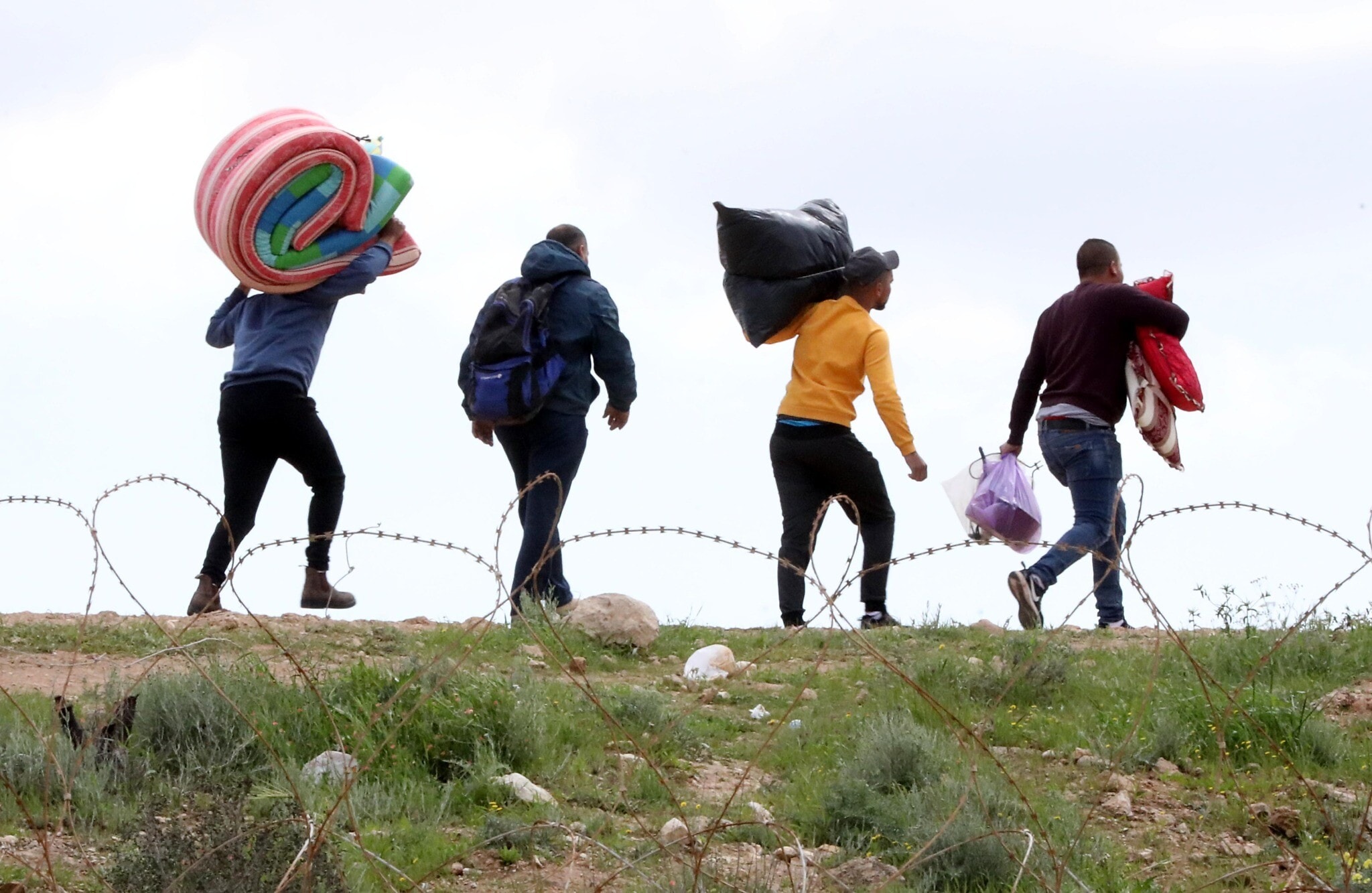 פועלים פלסטינים נכנסים לישראל דרך חור בגדר, לאחר שכניסתם נאסרה בגלל הקורונה, 22 במרץ 2020 (צילום: Wisam Hashlamoun/Flash90)