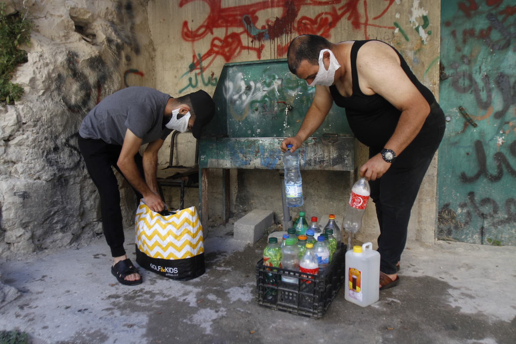 פלסטינים ממלאים מים בג&#039;ריקנים בגדה המערבית (צילום: Nasser Ishtayeh/Flash90)