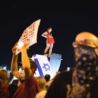 הסטודנטית לעבודה סוציאלית מסירה את חולצתה על פסל המנורה ליד הכנסת. הפגנת בלפור 21.7.2020 (צילום: יאיר מיוחס)