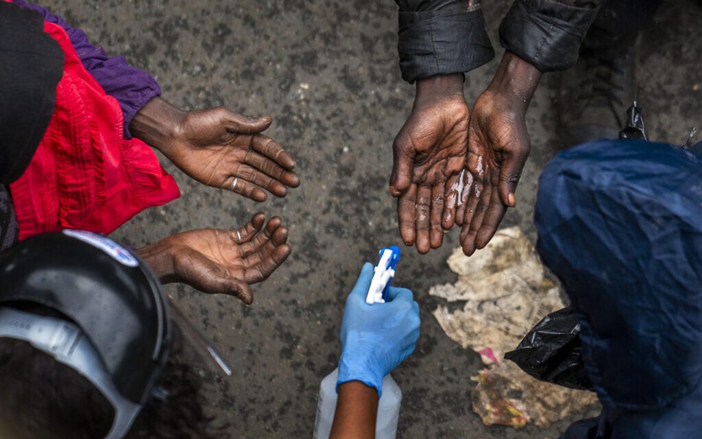 דרי רחוב נדרשים לחטא את ידיהם לפני קבלת תרומות מזון במהלך הסגר הקורונה, יוהנסבורג, אפריל 2020 (צילום: AP Photo/Jerome Delay)