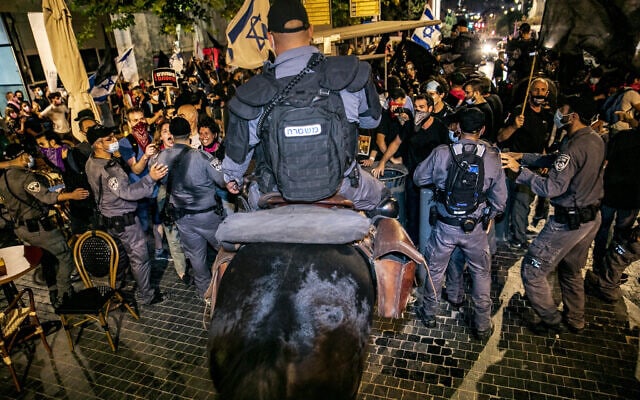 פרש משטרתי דוחק במפגינים. אבי קדיש נראה מימין, בחולצה שחורה, אוחז בדגל. 22 באוגוסט 2020 (צילום: אוליבייה פיטוסי/פלאש90)