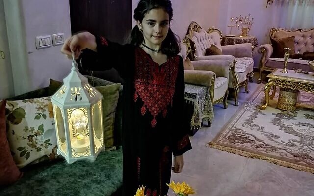 ילדה ממשפחת אבו סביי ממזרח ירושלים במסורת הרמדאן, אוחזת מנורה בסלון בית המשפחה, לפני שנהרס (צילום: איאד אבו סביי)