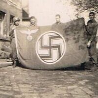 אביה של המחברת, טוראי אלכסנדר ברויאר (משמאל), עם דגל נאצי שהחרים עם חבריו בעיירה גרמנית קטנה (צילום: באדיבות הדי אברמוביץ)
