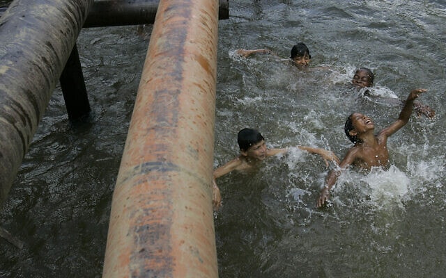 ילדים משחקים בנהר שבו צינורות נפט עוברים מעל פני השטח באקוודור, אוגוסט 2008. נשיא אקוודור התייצב לצד 30,000 התובעים בתביעה הייצוגית שכונתה &quot;צ&#039;רנוביל של האמזונס&quot;, בגלל הרעלה אטית של יערות גשם עם מיליוני ליטרים של נפט ומיליארדי שפכים רעילים (צילום: AP Photo/Dolores Ochoa)