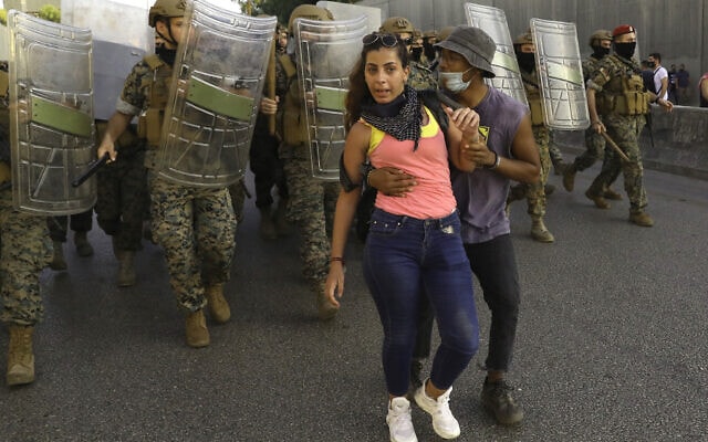מפגין נגד השלטון מגן על חברתו מפני חיילים במהלך מחאה ליד ביירות, 12 בספטמבר 2020 (צילום: AP Photo/Bilal Hussein)