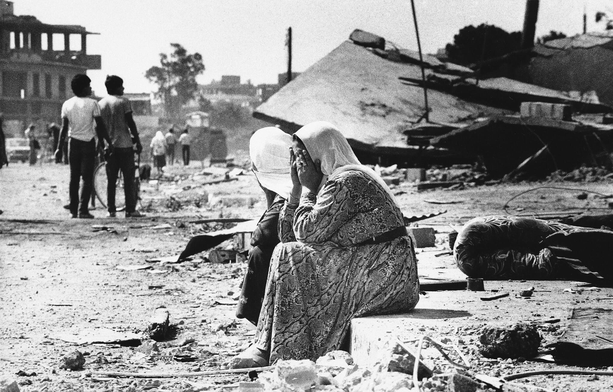 שתי נשים פלסטיניות בוכות על שפת מדרכה במחנה הפליטים סברה במערב ביירות, לבנון, 19 בספטמבר 1982, לאחר שמצאו גופות של קרובי משפחה (צילום: AP Photo/Bill Foley)