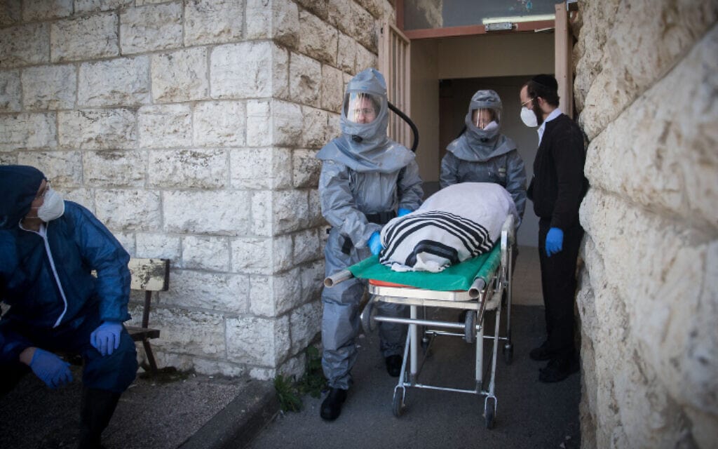 עובדי חברה קדישא נושאים גופה של חולה שמת מקורונה בירושלים, 29 במרץ 2020 (צילום: יונתן זינדל, פלאש 90)