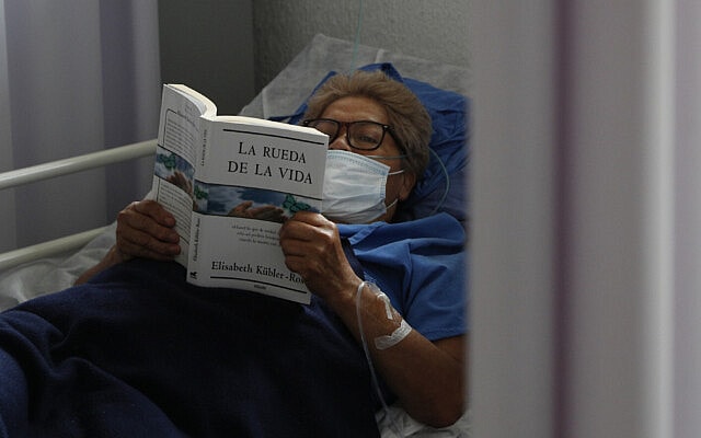חולת קורונה בבית חולים במקסיקו קוראת את ספרה של אליזבת קובלר-רוס, &quot;גלגל החיים&quot; (צילום: AP Photo/Rebecca Blackwell)