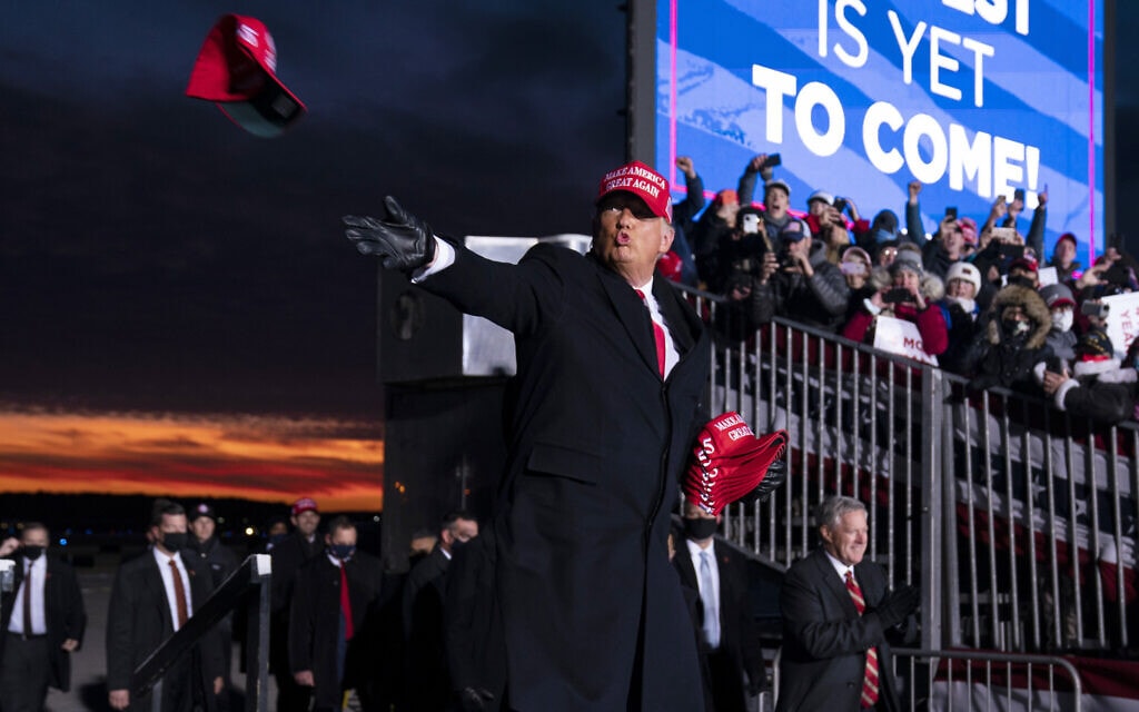 דונלד טראמפ זורק כובעים לתומכיו, בשדה התעופה צ'רי קפיטל, במישיגן, 2 בנובמבר 2020 (צילום: AP Photo/Evan Vucc)