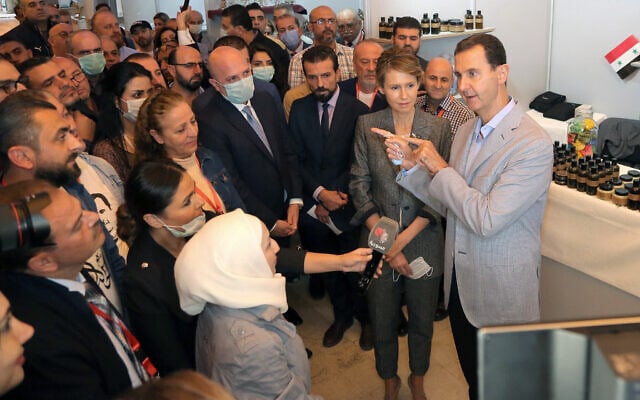 בתצלום, שסופק על ידי עמוד הפייסבוק של נשיאות סוריה, אסד ואשתו אסמה מדבר עם אנשים במהלך ביקור בתערוכה בדמשק, נובמבר 2020 (צילום: Syrian Presidency Facebook page via AP)