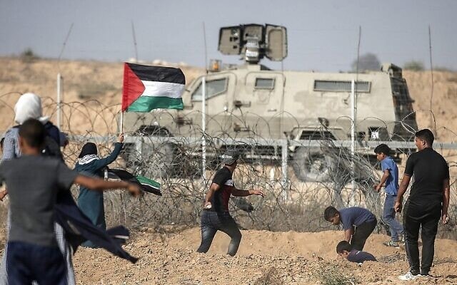 מפגינים פלסטינים מיידים אבנים לעבר כוחות הביטחון הישראליים במהלך הפגנות לאורך הגבול עם ישראל, ממזרח לחאן יונס בדרום רצועת עזה, 12 ביולי 2019 (צילום: MAHMUD HAMS / AFP)