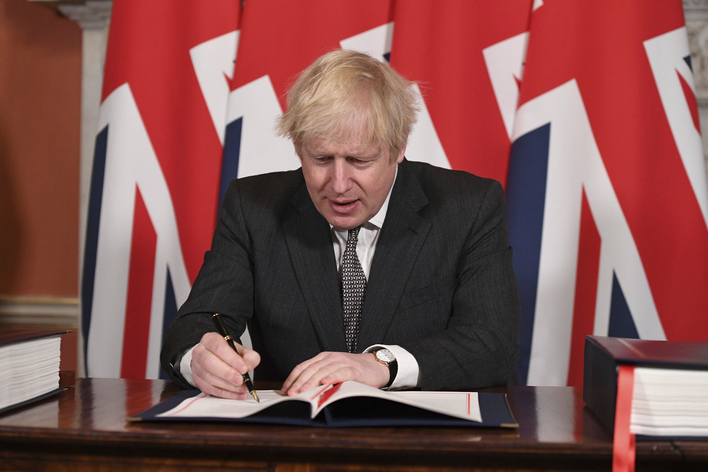 בוריס ג&#039;ונסון חותם על הסכם הסחר בין בריטניה והאיחוד האירופי. 30 בדצמבר 2020 (צילום: Leon Neal/Pool via AP)