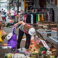 אישה מלקטת מהרצפה פירות וירקות שהושלכו בשוק. יולי 2020 (צילום: Yossi Aloni/Flash90)