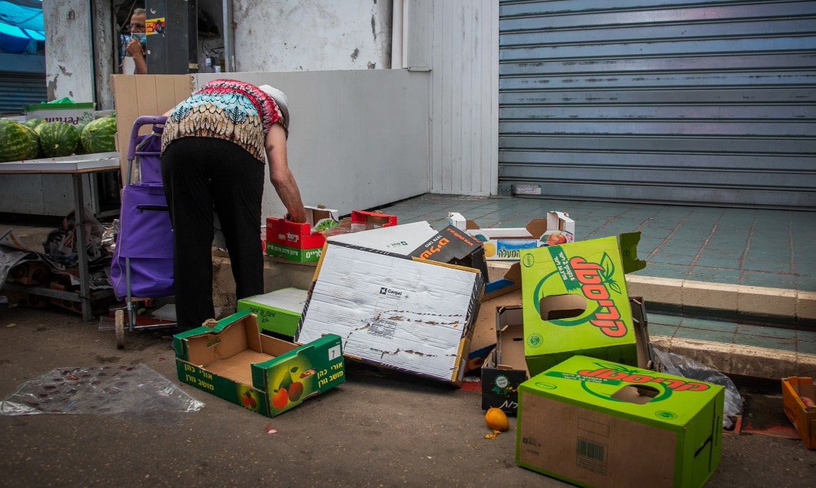 אישה מלקטת מהרצפה פירות וירקות שהושלכו בשוק. יולי 2020 (צילום: Yossi Aloni/Flash90)