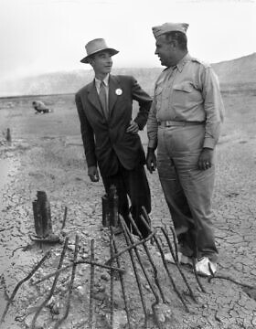 פיזיקאי האטום רוברט אופנהיימר וקולונל לסלי גרובס לצד שרידים באתר ניסוי טריניטי בספטמבר 1945, חודשיים לאחר הניסוי בפצצה וזמן קצר לאחר סיום מלחמת העולם השנייה (צילום: רשות הכלל, באמצעות ויקישיתוף)