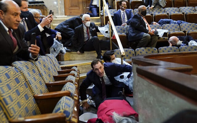 נוכחים באולם בית הנבחרים מתחבאים בין הכסאות בזמן שתומכי טראמפ פורצים לגבעת הקפיטול, 6 בינואר 2021 (צילום: AP Photo/Andrew Harnik)