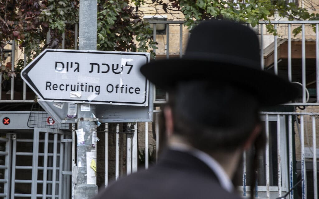 גבר חרדי חולף על פני שלט המצביע על לשכת הגיוס בירושלים, 5 בדצמבר 2019 (צילום: אוליבייה פיטוסי/פלאש90)