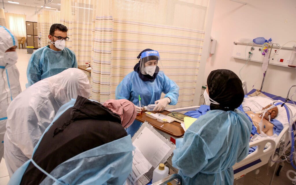 צוות רפואי מטפל בחולה קורונה בבית החולים דורה בגדה המערבית, 14 בינואר 2021 (צילום: Wisam Hashlamoun/Flash90)