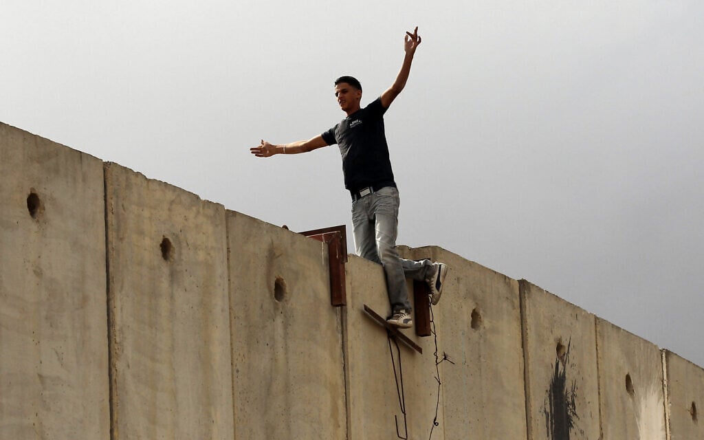 פלסטיני עומד על גדר ההפרדה ליד מחסום קלנדיה, בין רמאללה וירושלים. 23 בספטמבר 2011 (צילום: נתי שוחט/פלאש90)