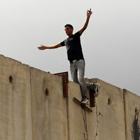 פלסטיני עומד על גדר ההפרדה ליד מחסום קלנדיה, בין רמאללה וירושלים. 23 בספטמבר 2011 (צילום: נתי שוחט/פלאש90)