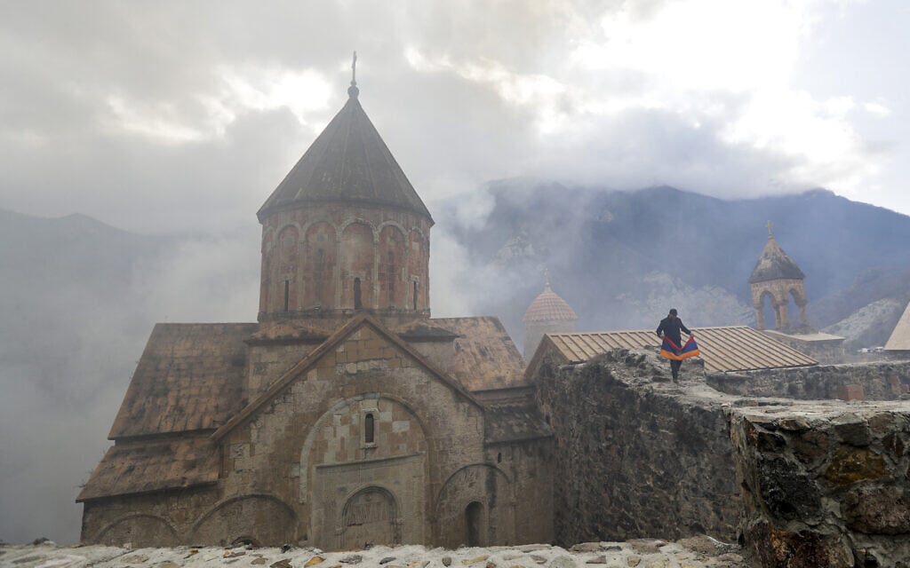 ארמני עם דגל ארמניה במנזר מהמאה ה-13 בחבל נגורנו קרבאך, 13 בנובמבר 2020 (צילום: AP Photo/Sergei Grits)